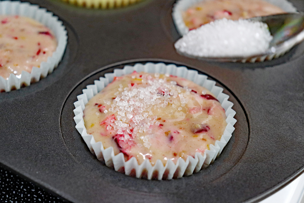 Sprinkling sugar on muffins before baking