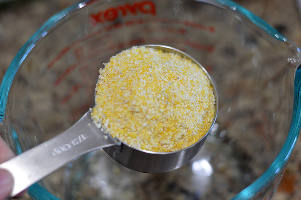 Measuring cup full of cornmeal for Vegan Corn Fritters