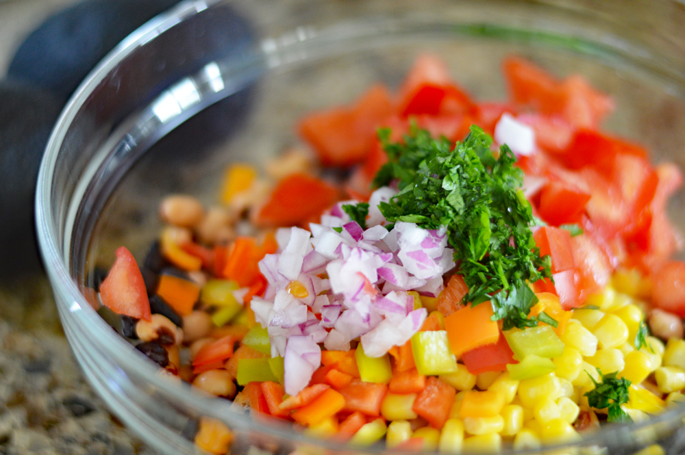 Bowl of ingredients including red onion and parsley for Cowboy Caviar a/k/a "Texas Caviar"