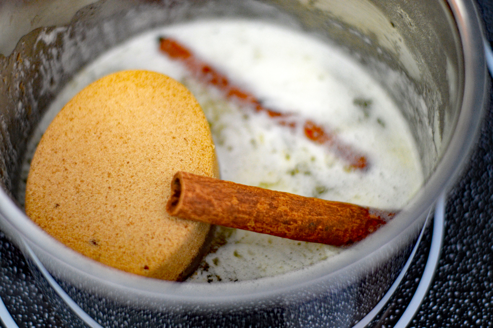 Pan with melted butter, sugar and cinnamon sticks for Classic Candied Sweet Potatoes Recipe