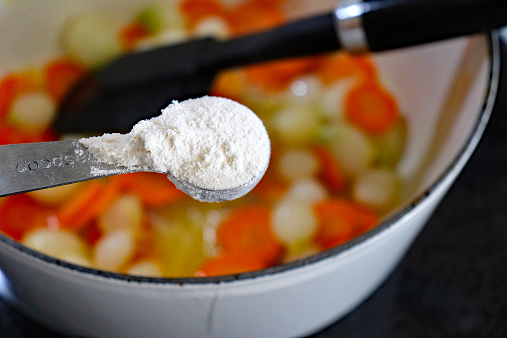 Teaspoon full of flour over carrots and onion mixture