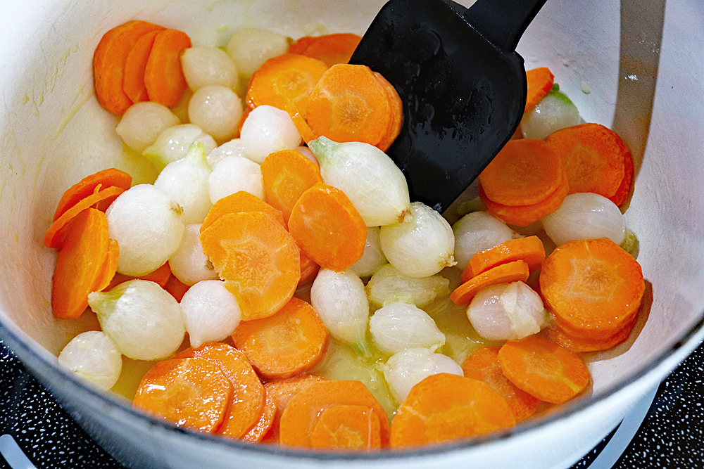 Pot of onions and carrots with spatula