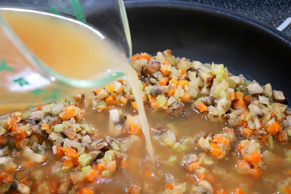 Adding broth to pan of sauteed vegetables