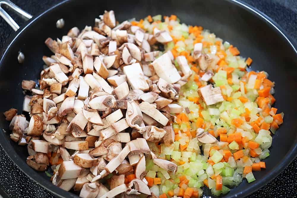 Diced vegetables and mushrooms in a saute pan