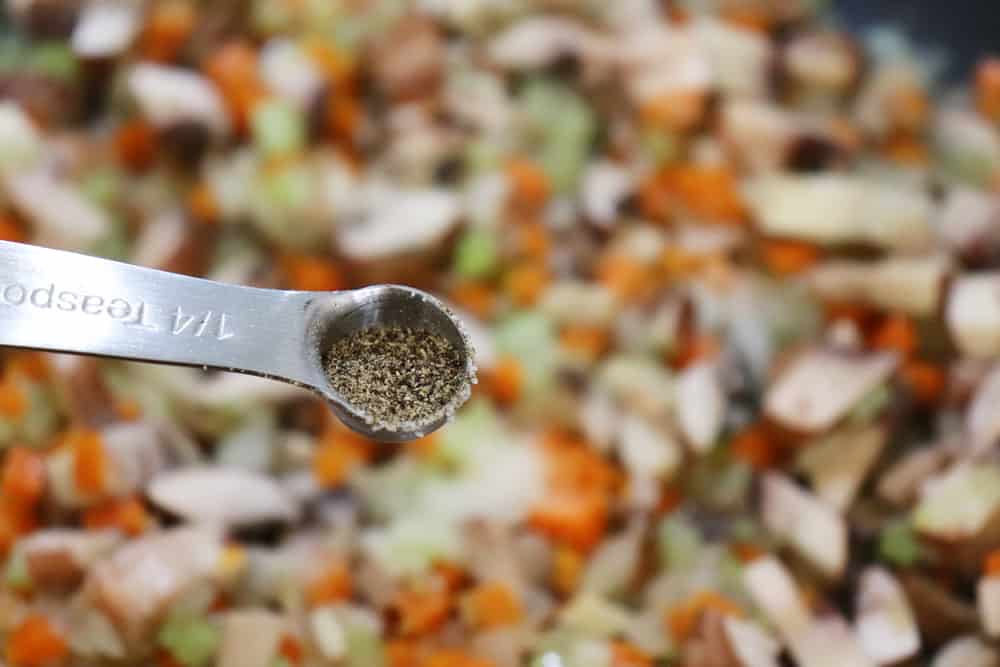 1/4 teaspoon of pepper being added to sauteed vegetables