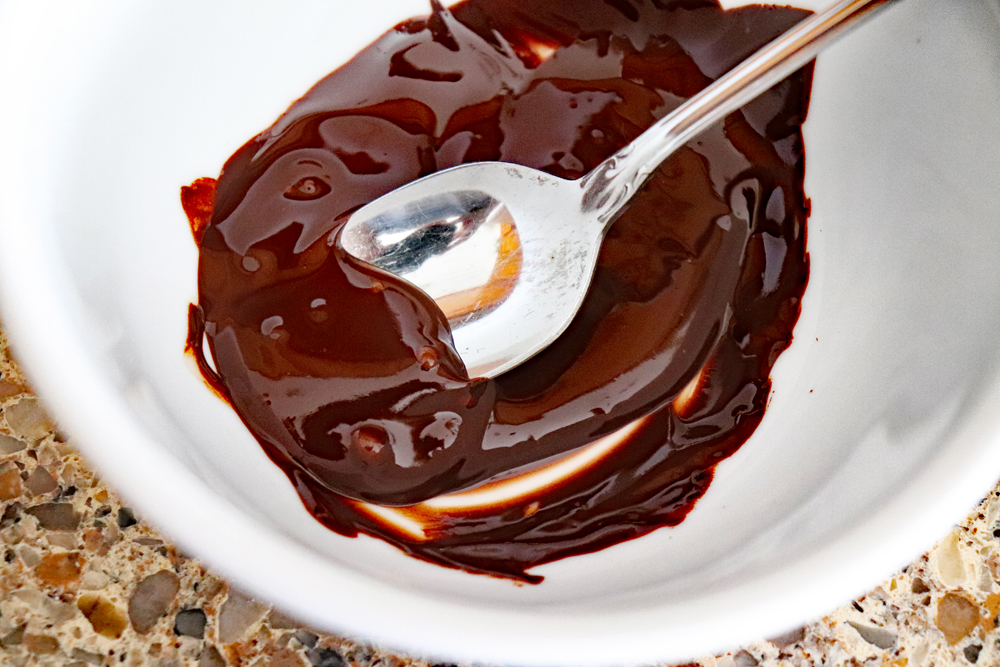 Melted chocolate in a white bowl with a spoon