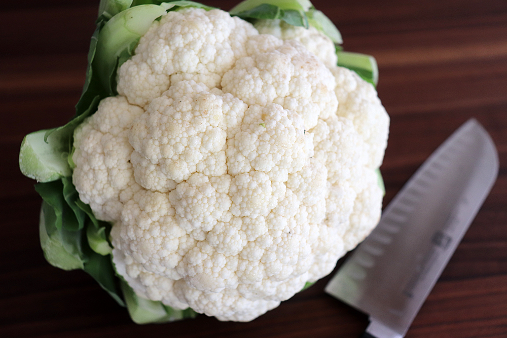 Head of cauliflower with knife on cutting board