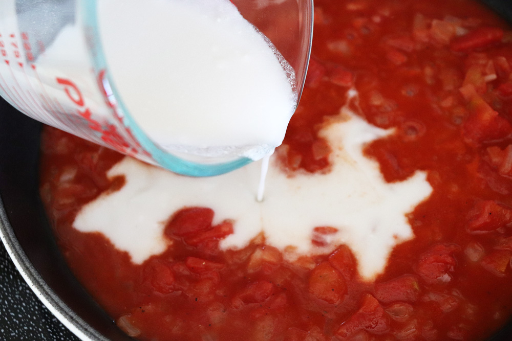 Adding coconut cream to the diced tomatoes