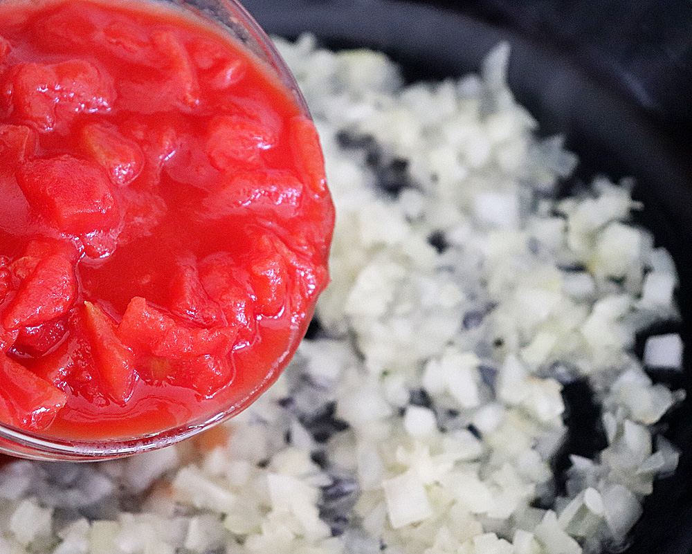 Adding diced tomatoes to the sauteed onions