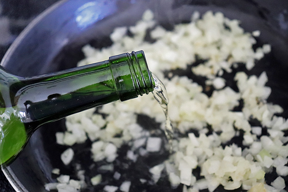 Adding white wine to sauteed onions in skillet