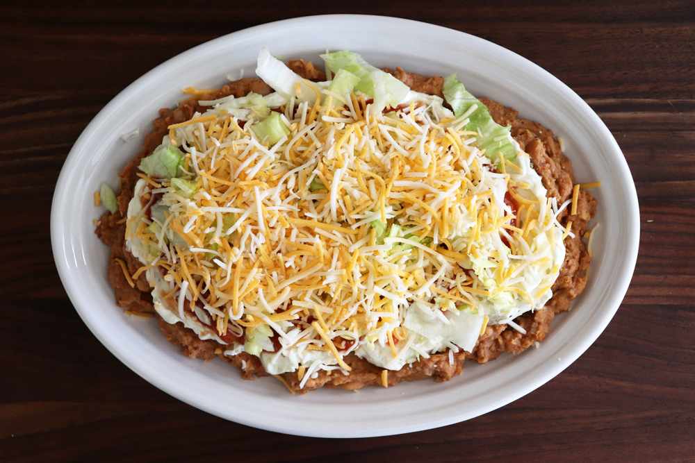 Adding shredded cheese to the lettuce layer