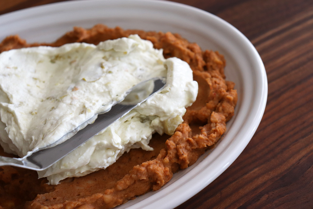 Spreading cream cheese layer onto refried beans