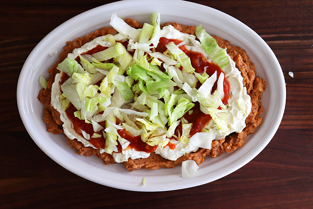 Adding shredded lettuce to the salsa layer