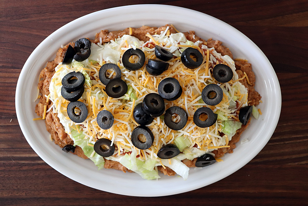 Adding sliced olives to the cheese layer