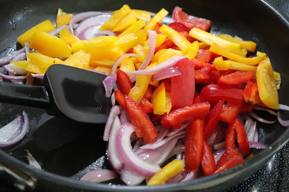 Adding peppers to the red onions