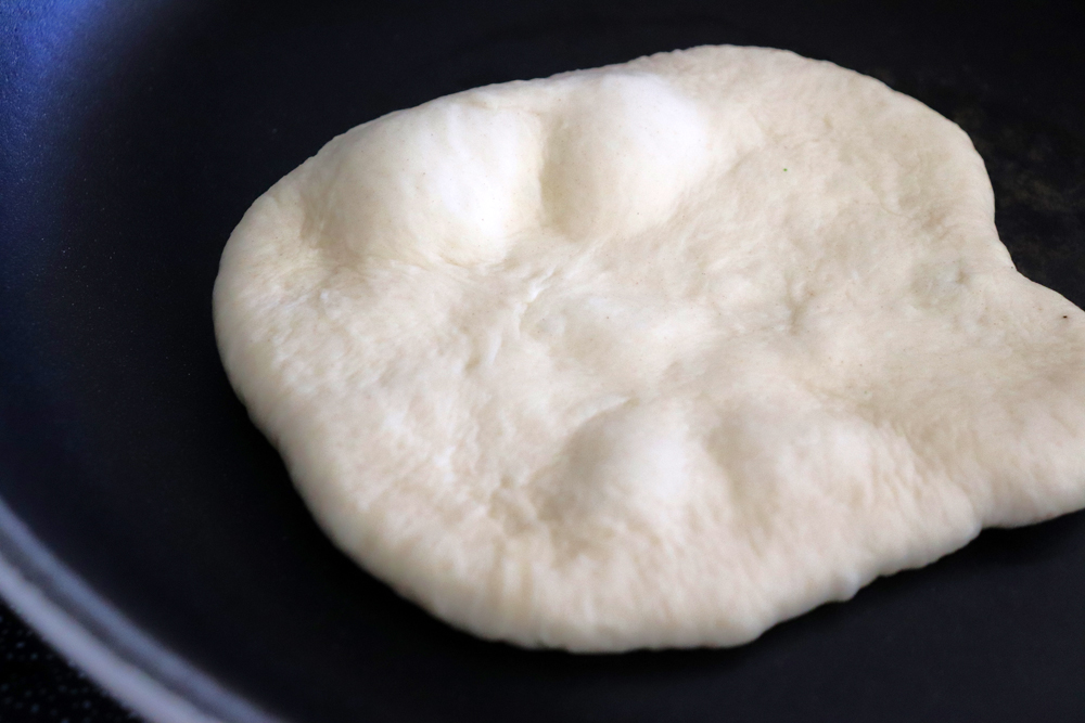 Cooking the Naan dough on a hot pan