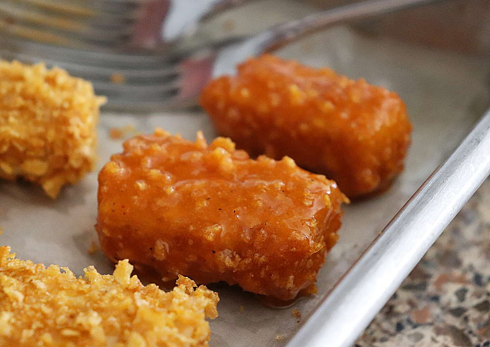 Saucing the nuggets for Vegan Nashville Hot Tofu Nuggets Recipe