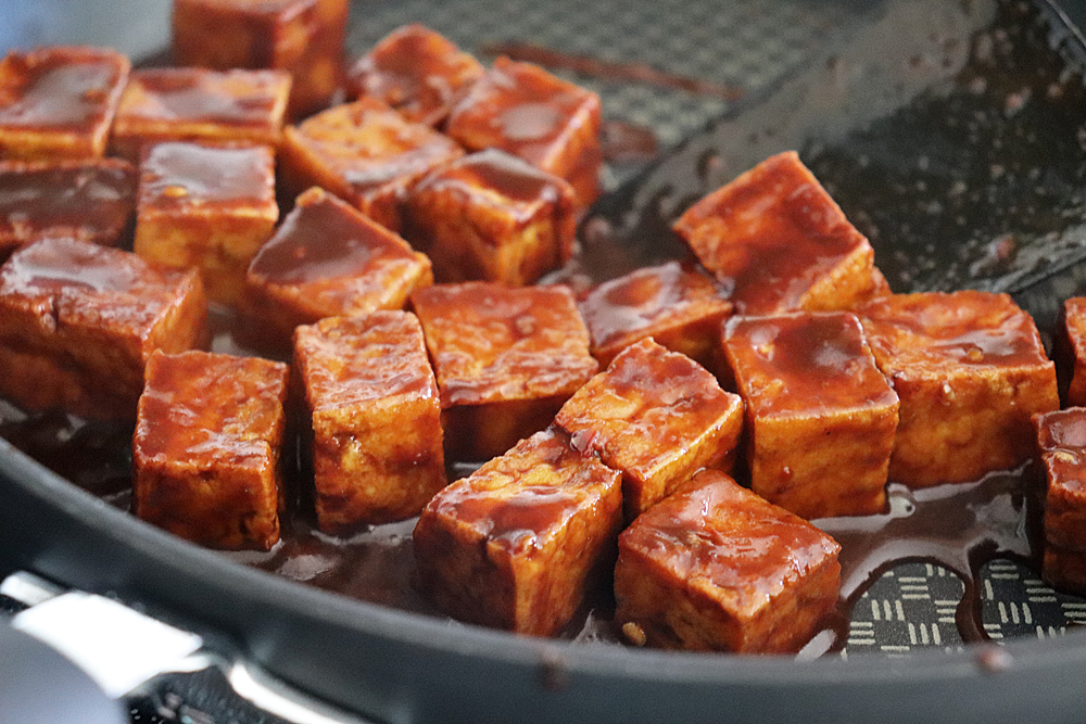 Tossing the tofu with the glaze until thickened