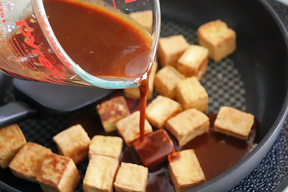 Pouring Hoisin mixture over the tofu